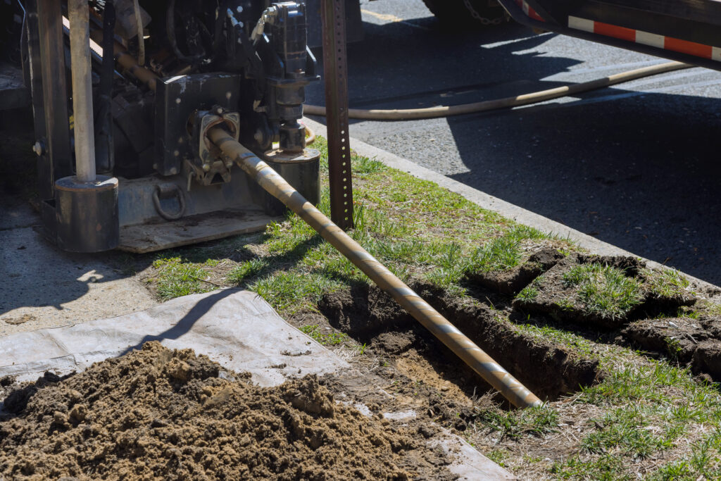 Low-angle view of trenchless laying of communications, fiber optic and water pipes with horizontal directional drilling technology machine work process.