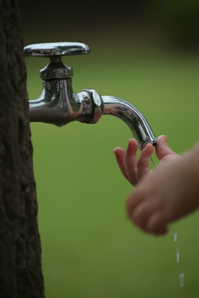 Child's hands under a running outdoor spigot in Westchester County.